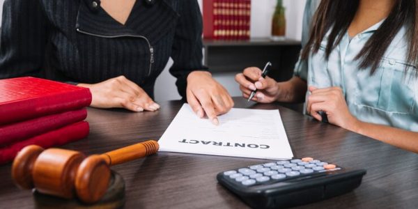 black-woman-pointing-document-near-lady-with-pen-table-with-calculator-gavel_23-2148042590